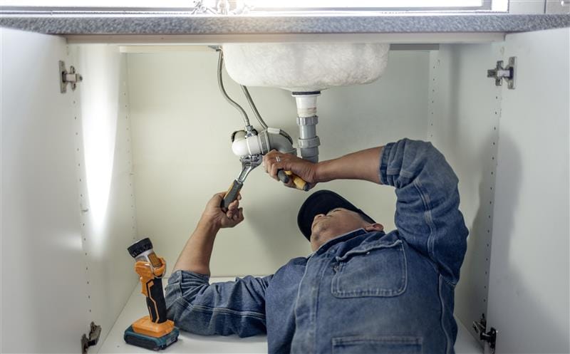 Plumber repairing pipes beneath a bathroom sink in Rohnert Park